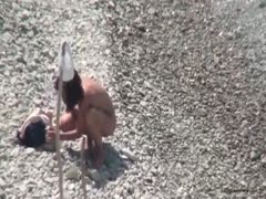 A thin, attractive housewife with white brunette hair on a pebbly beach